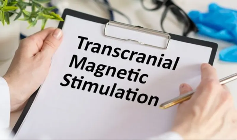Clinician holding a clipboard labeled Transcranial Magnetic Stimulation