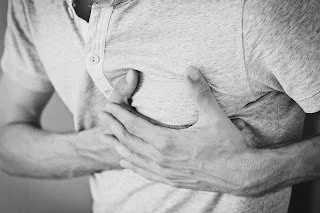 Man in a T-shirt gripping his chest with both hands