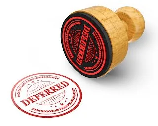 Wooden rubber stamp next to a red circular DEFERRED imprint